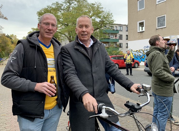 Zwei Männer vor dem Eintracht-Stadion, einer mit Fahrrad.