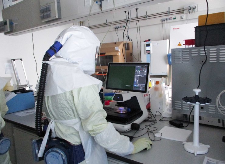 Eine Person in weißer Schutzkleidung steht an einem Labortisch.