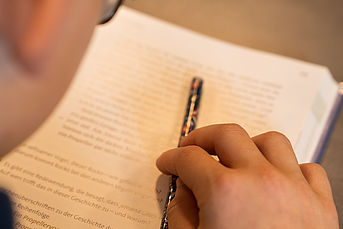 Ein Kind schreibt auf ein Blatt Papier.