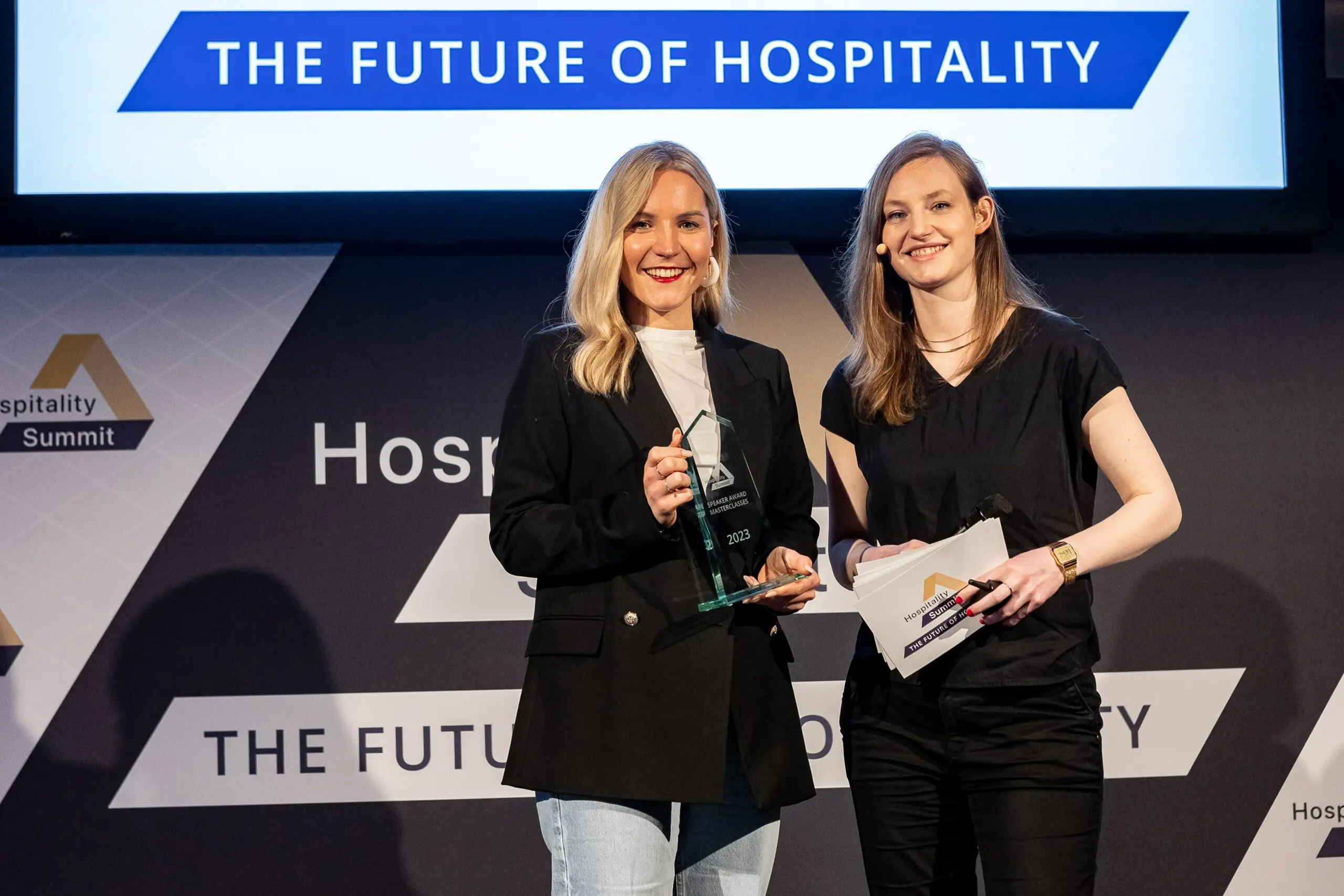 Zwei junge Frauen auf einer Bühne bei einer Preisverleihung. 