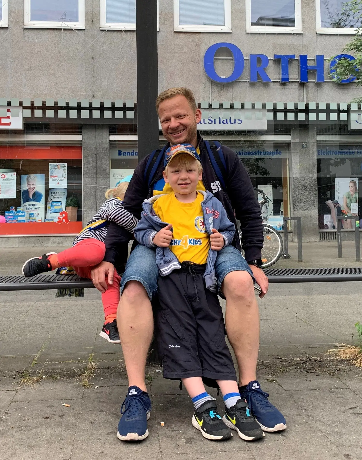 Ein Vater und sein Sohn sitzen an der Bushaltestelle in Braunschweig.