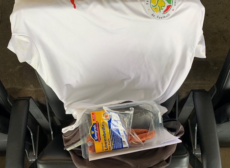 Ein Fußballtrikot und eine Packung Würste liegen auf einem Stadionsitz.