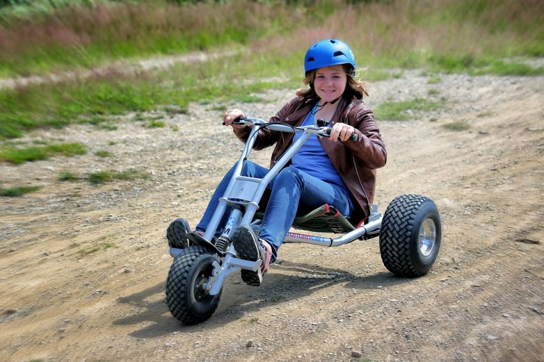 Ein Mädchen fährt auf einem Dreirad den Bocksberg hinunter.