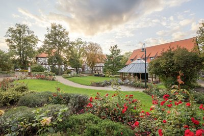 Man blickt über Rosenbeete auf den Gradierpavillion im Rosengarten, einer Parkanlage in Salzgitter-Bad.