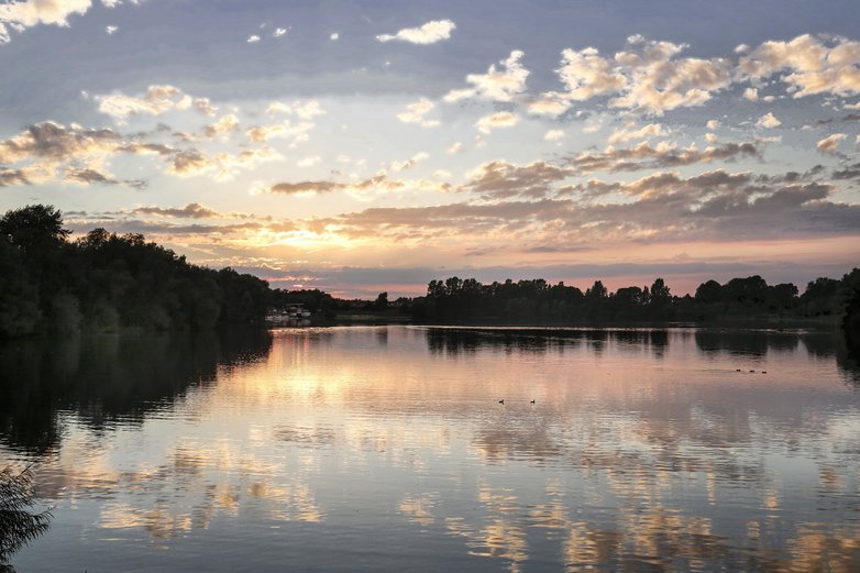 Der Sonnenuntergang am Eixer See spiegelt sich auf der Wasseroberfläche.