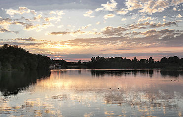 Der Sonnenuntergang am Eixer See spiegelt sich auf der Wasseroberfläche.