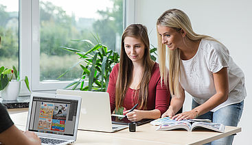 Auszubildende bei Sport-Thieme im Büro in Helmstedt schauen gemeinsam auf einen laptop-Bildschirm. 