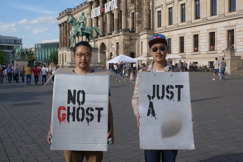 Zwei Männer halten ein Plakat vor dem Braunschweiger Schloss hoch.