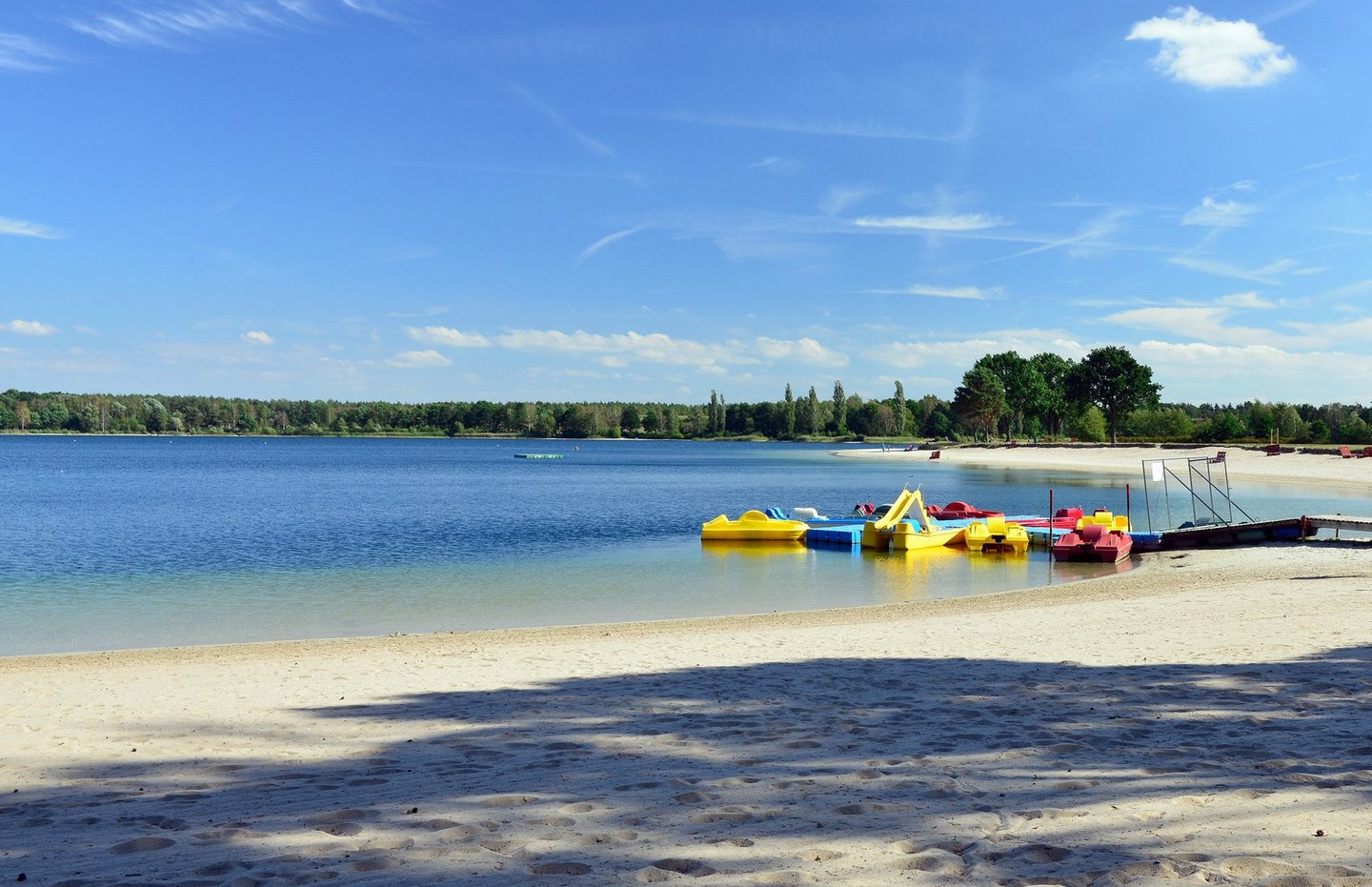 Man blickt auf Tretboote am Strand des Tankumsees