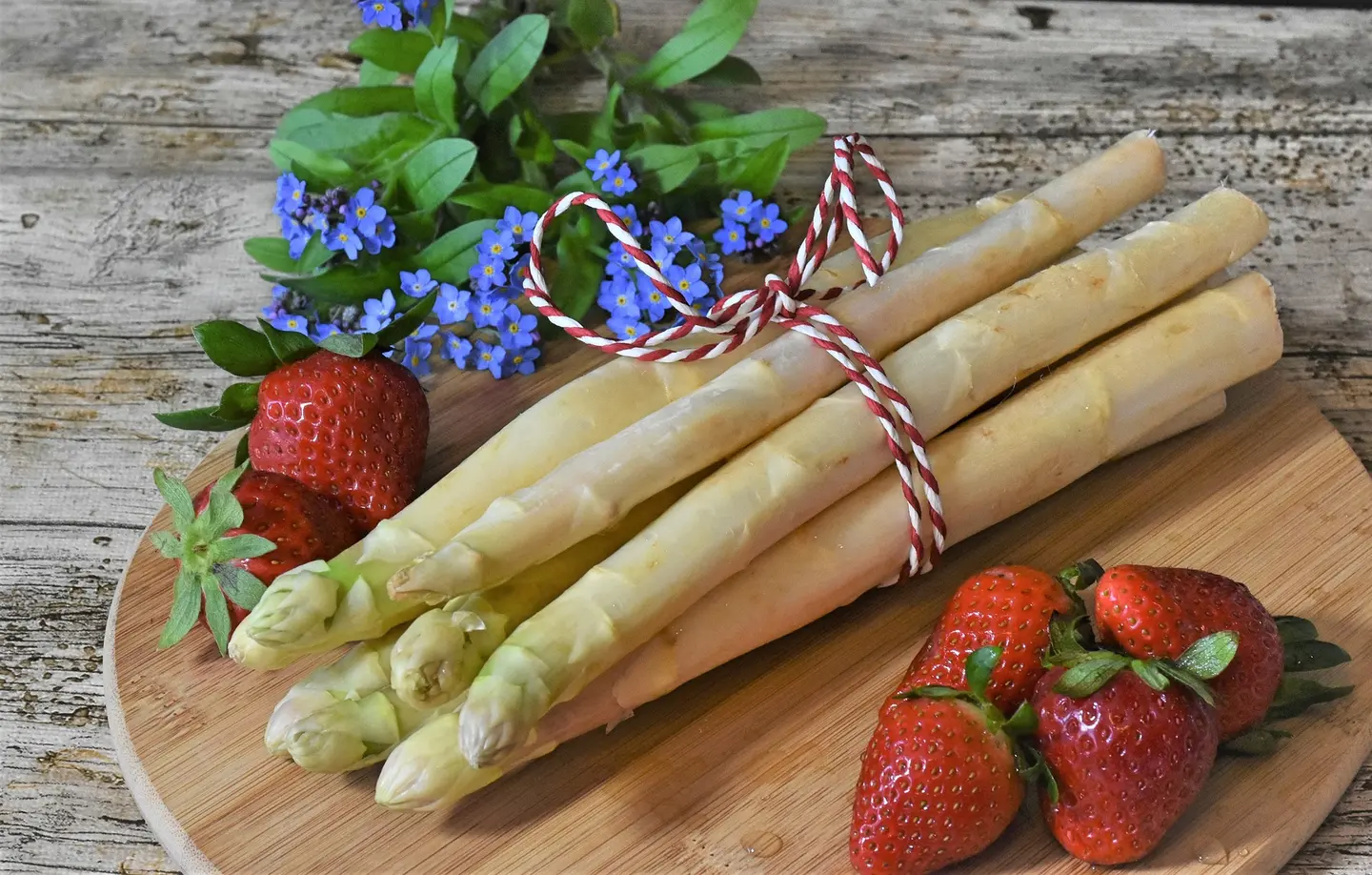 Spargel auf einem Tisch, daneben Erdbeeren: Ein Genuss.