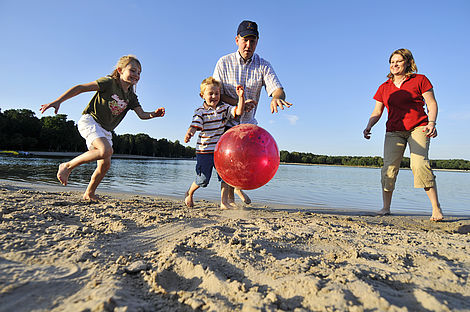 Familie spielt Fußball am Strand des Tankumsees im Landkreis Gifhorn.