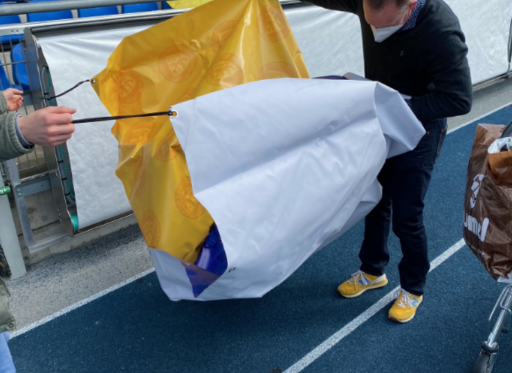 Ein Mann faltet eine Fanclub-Fahne auf.