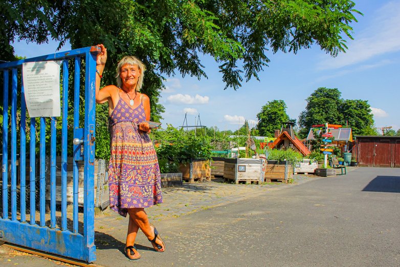 Eine Frau lehnt am Eingangstor zum Stadtgarten Bebelhof.
