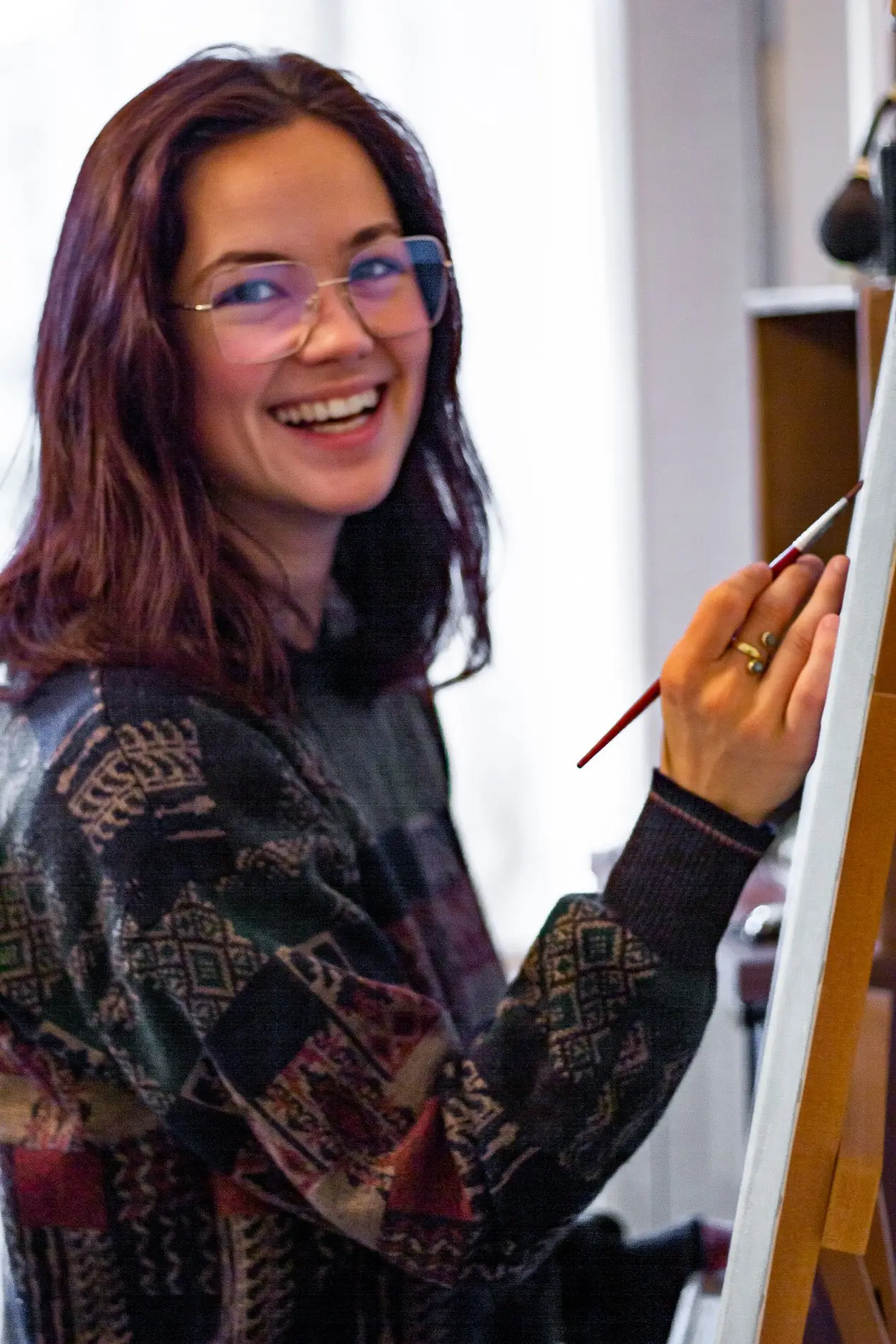 Eine Frau sitzt an einer Staffelei und malt.