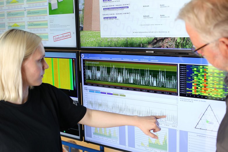 Technologie-Berufe im Austausch. Leonie mit PDV-Geschäftsführer Tristan Niewisch vor einem Daten-Screen mit Live-Analyse.