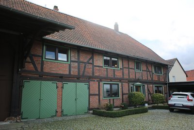 Ein Auto parkt auf dem Hof eines Bauernhauses.