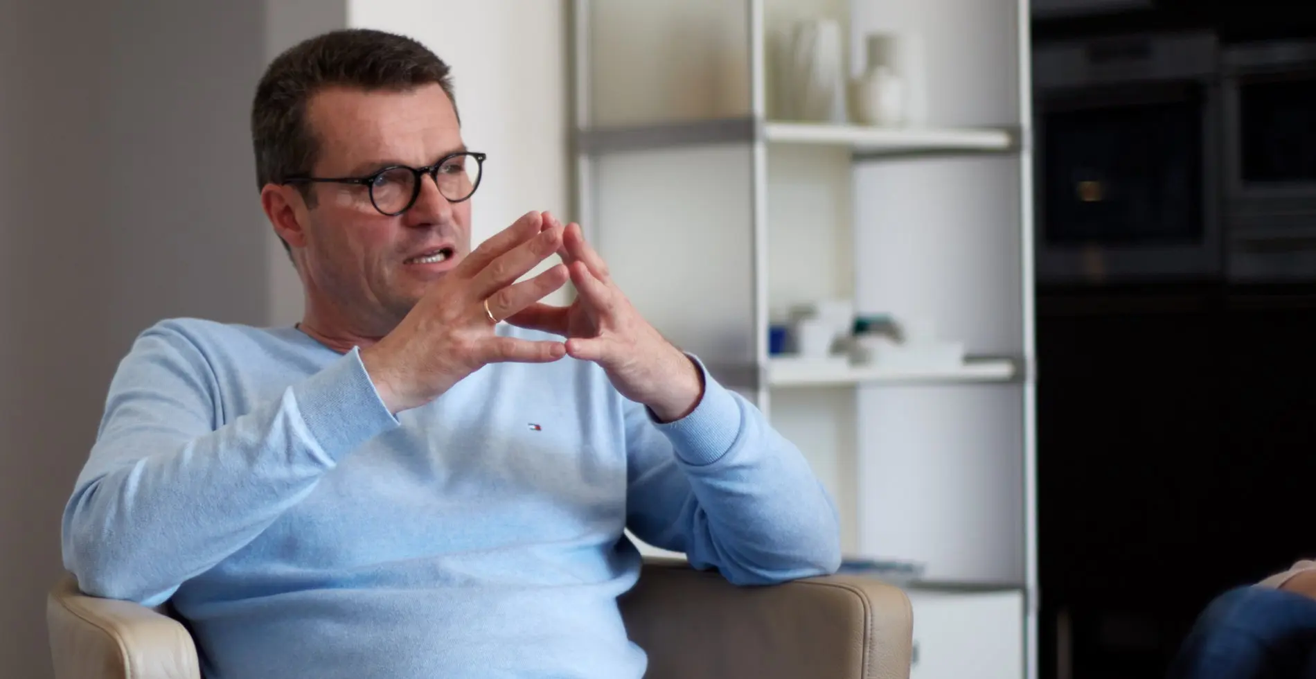 Ein Mann mit Brille sitzt auf einem Stuhl.