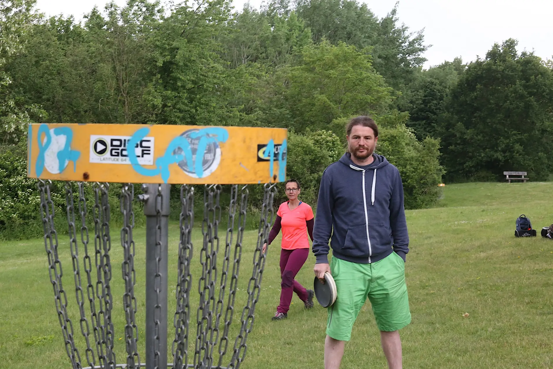 Ein Mann und eine Frau stehen hinter einem Discgolf-Korb.