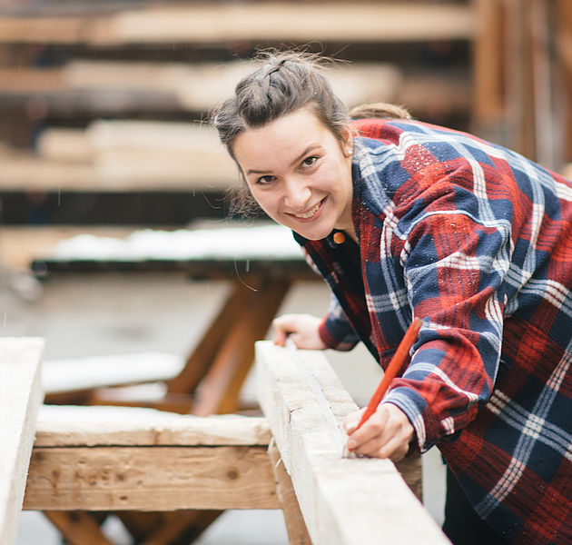 Eine Frau bearbeitet einen Holzbalken in einer Werkstatt. (Bildrechte: Handwerkskammer Braunschweig Lüneburg Stade)