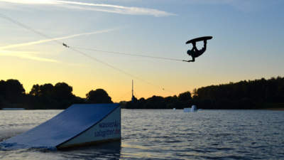 Ein Wakeboarder springt über eine Rampe im Salzgittersee.