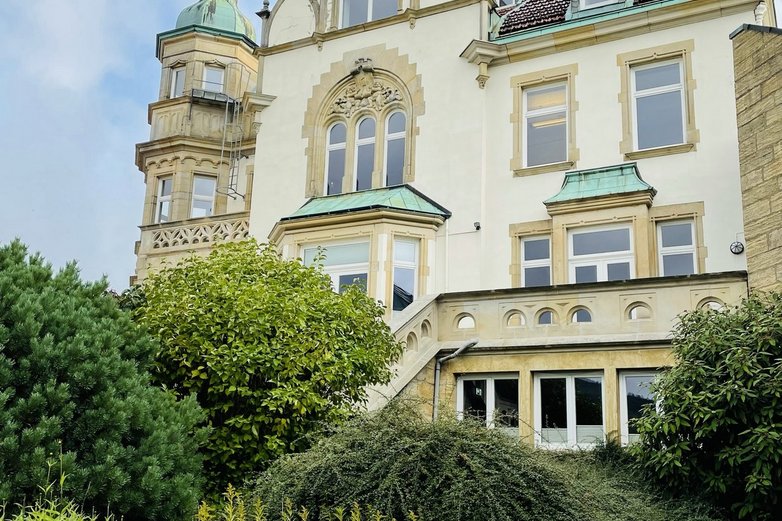 Das Bild zeigt einen Garten vor einem Altbau.