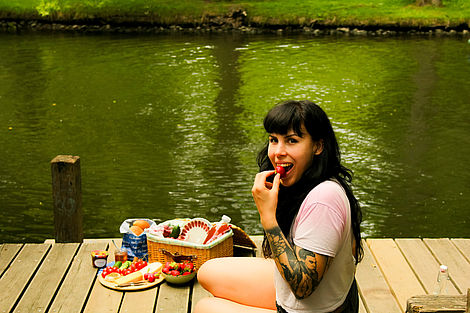 Eine junge Frau frühstückt am Wasser.