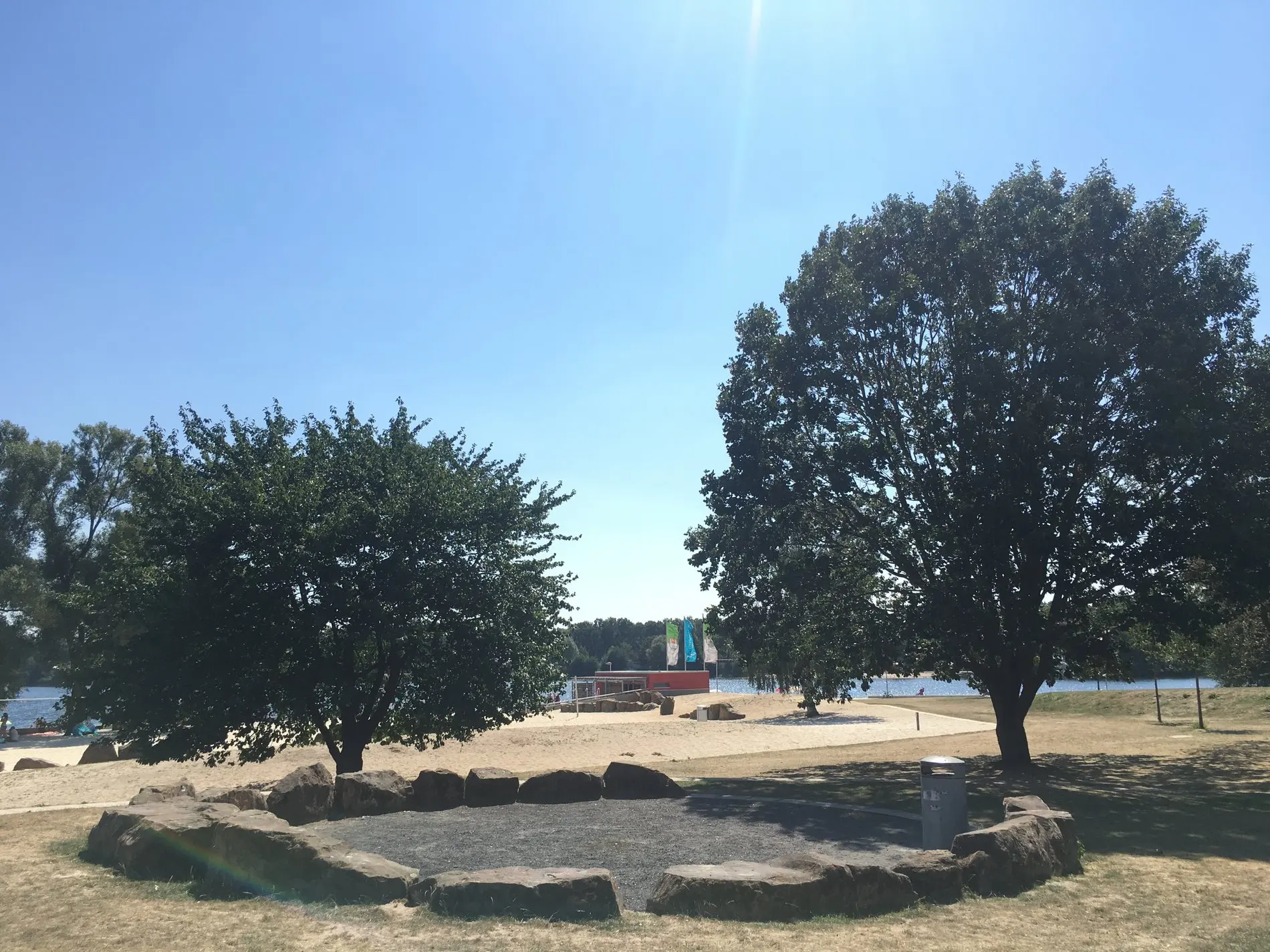 Eine Grillstelle zwische  zwei Bäumen, im Hintergrund der Allersee in Wolfsburg.