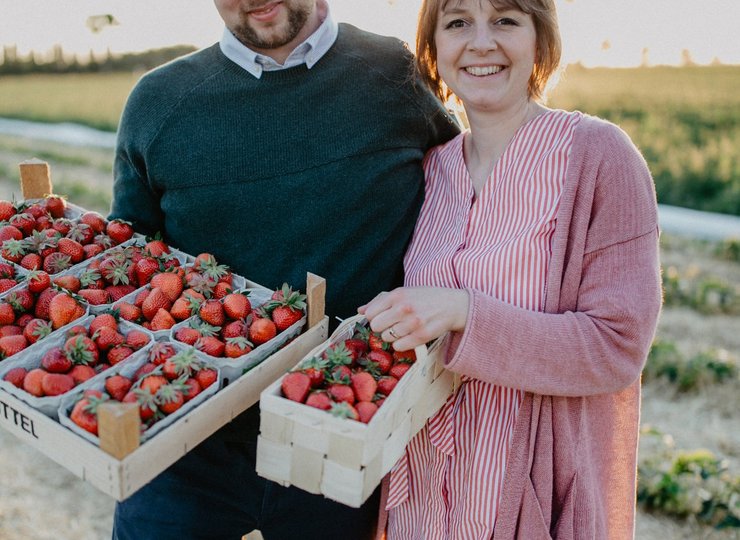 Eine Frau und ein Mann halten eine Erdbeerenkiste.