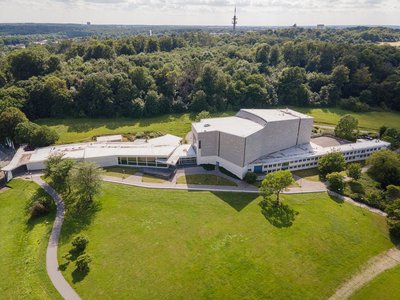 Ein Theater, das nahe eines Waldstücks gelegen ist.