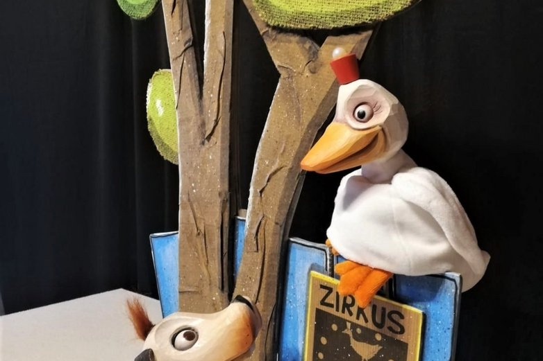 Zwei Puppen stehen auf einer kleinen Bühne.