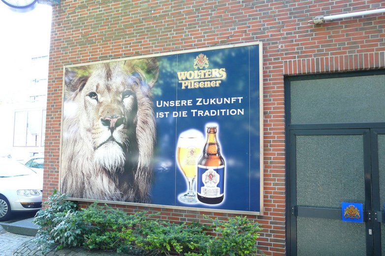 Ein Plakat zeigt einen Löwen, eine Flasche und ein volles Bierglas.