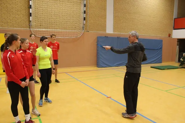 Ein Trainer redet mit einer Sportlerin und gestikuliert dabei.