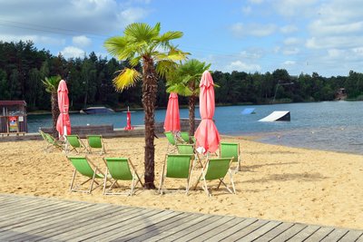 Man blickt auf die Wasserskianlage und Liegestühle am Strandufer des Bernsteinsees