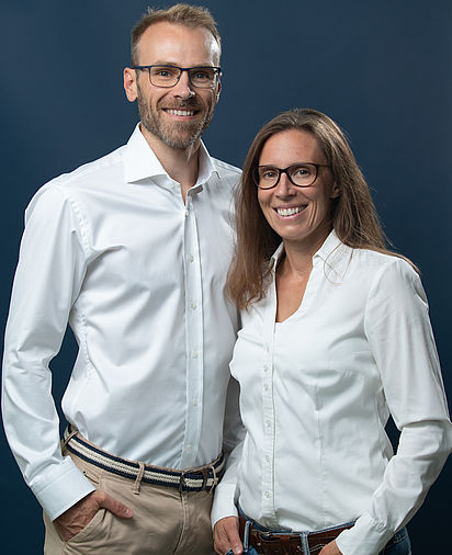 Eine Frau und ein Mann stehen nebeneinander, beide im weißen Hemd.