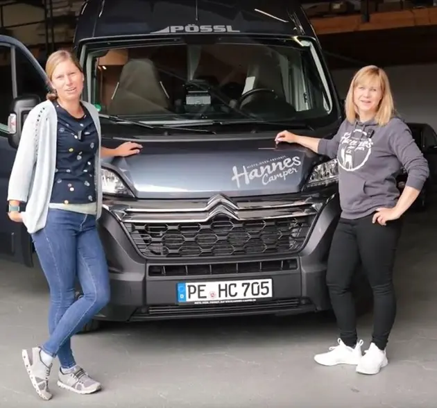 Zwei Frauen stehen an einem Camper-Bus.