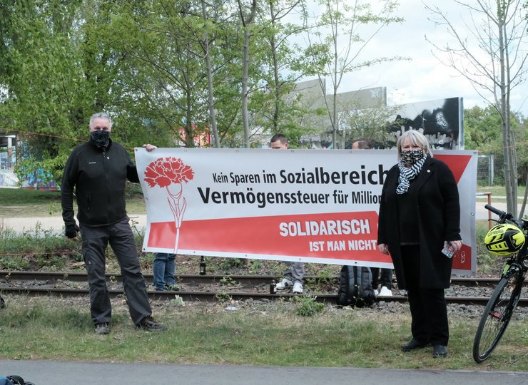 Zwei Gewerkschaftler stehen rechts und links eines Plakates.