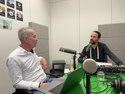 Zwei Männer in einem Hörfunkstudio unterhalten sich.