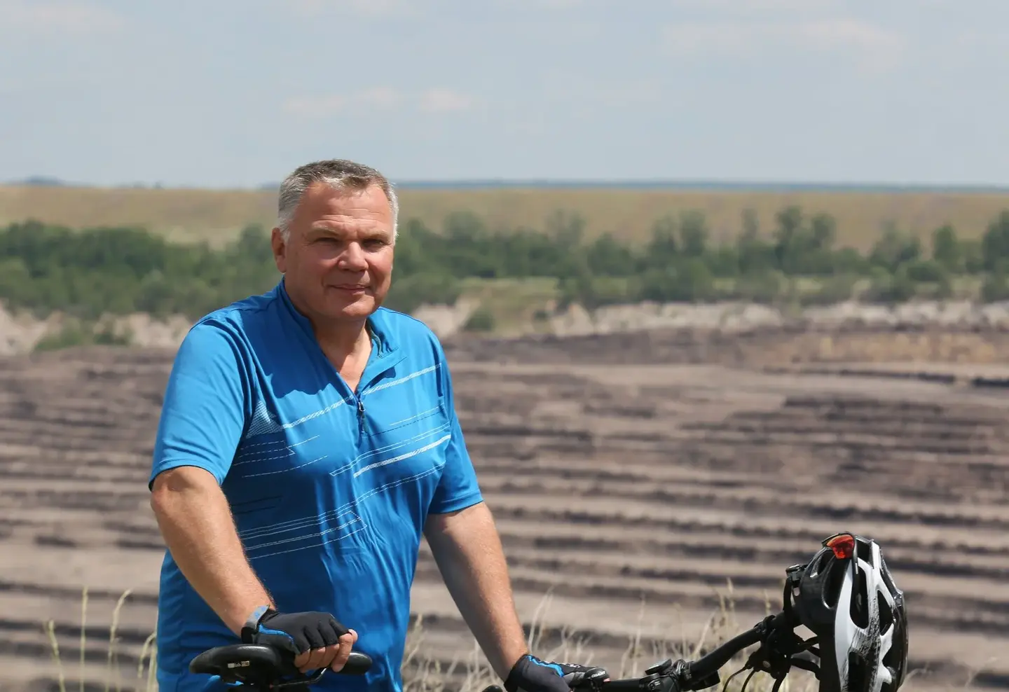 Ein Radfahrer posiert für ein Portrait vor einem alten Tagebau.