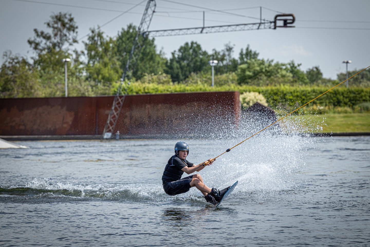 Man blickt auf einen Wakeboarder, der auf der Wassersportanlage des Allersees fährt.