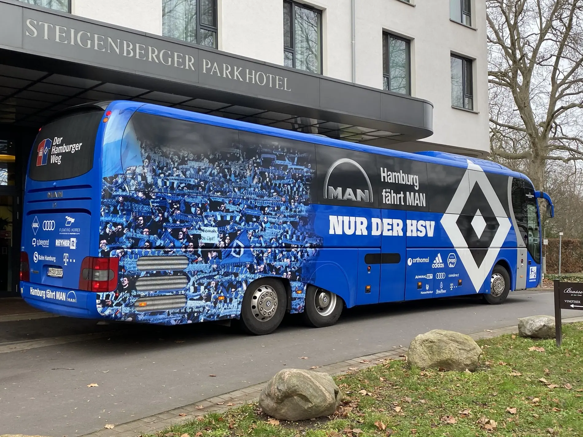 Ein blauer Bus parkt vor einem Hotel in Braunschweig.