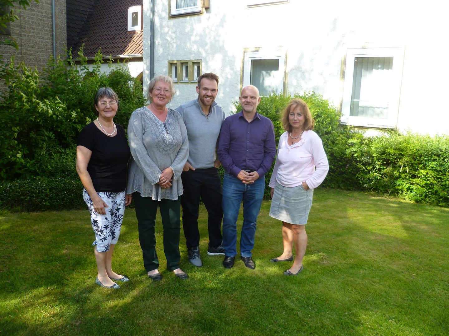 Der Vorstand des FreiwilligenZentrumSalzgitter e.V. in einem Garten vor grünen Büschen. 