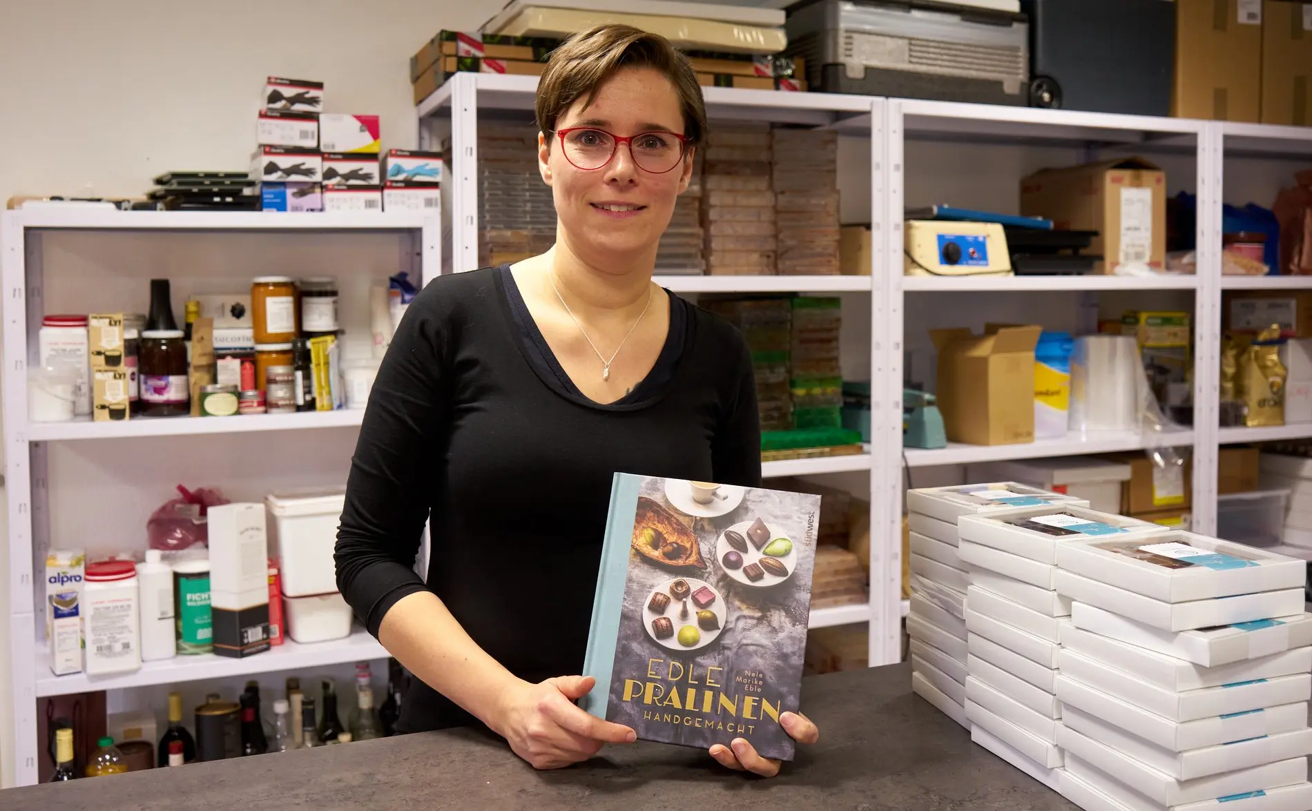 Eine Frau hält ein Buch vor sich in die Kamera. Es geht um Pralinen.