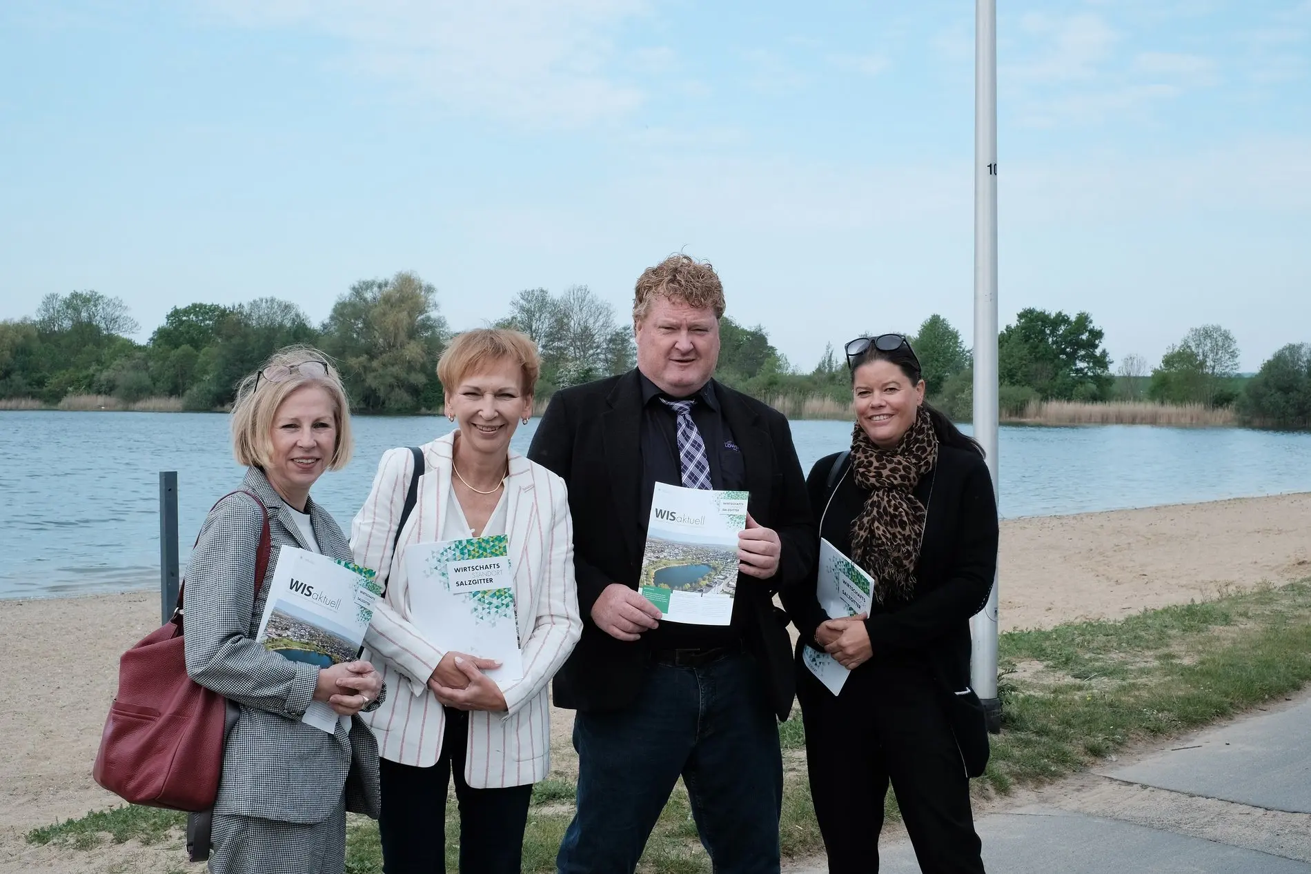 Drei Frauen und ein Mann stehen nebeneinander und lächeln. 
