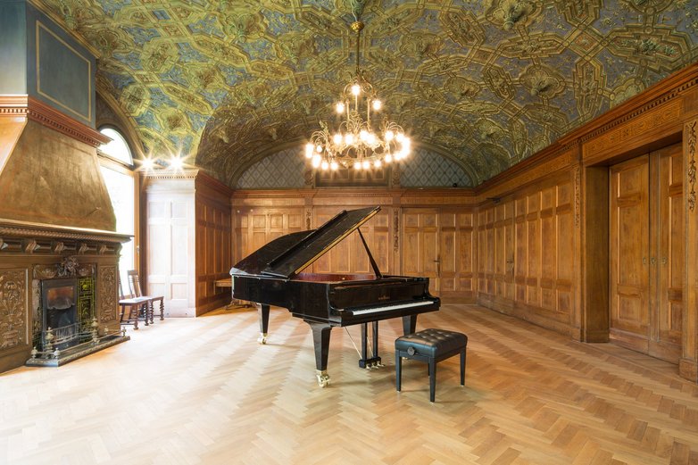 Ein kleiner, edler Saal mit einem schwarzen Flügel in der Mitte.