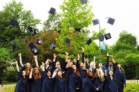 Absolventen der CJD International School Braunschweig-Wolfsburg werfen ihre Doktorhüte.