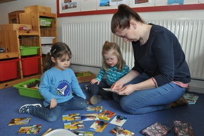 Jennifer Polo beim Spielen mit Hanzade und Frieda auf dem blauen Teppich.