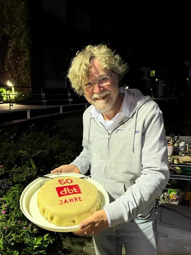 Ein Mann mit einer Jubiläumstorte in den Händen.