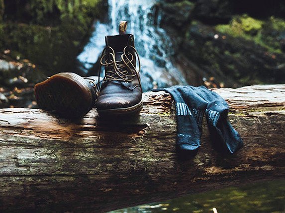 Wanderschuhe nebst Socken auf einem Baumstamm im Wald