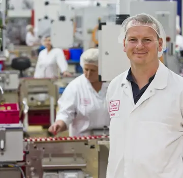 Mann mit Arbeitskleidung und Hygienehaube in Schokomanufaktur (Bildrechte: JR Die Schokoladenfabrik GmbH, Foto: Jörg Scheibe)