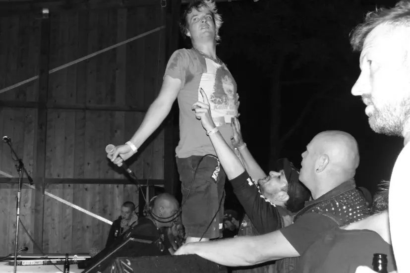 Ein Sänger steht am Rand der Musik-Bühne des UJZ Peine, Zuschauer dicht davor. 